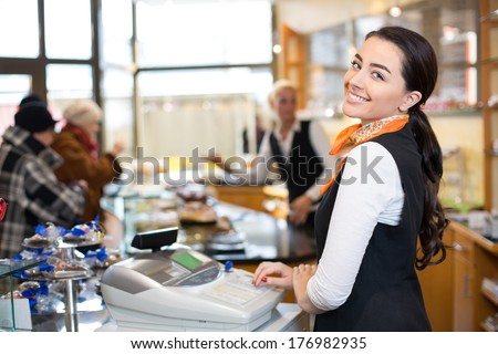 Saleswoman working at cash register or checkout counter in shop