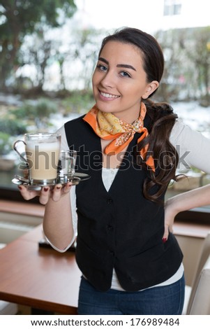 Waitress or server posing with cup of coffee in cafe or restaurant