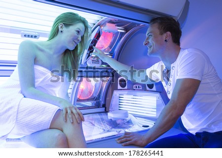 Staff employee in a solarium counseling customer or client at tanning bed