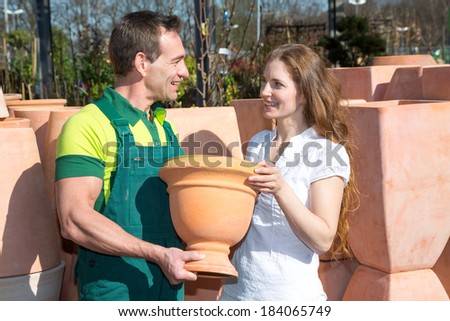 Employee in garden center selling pottery to customer or client