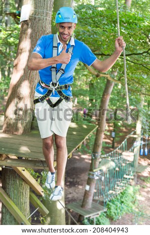 Man showing thumbs up while climbing in high rope course