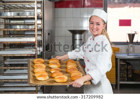 Baker presenting tray with pastry or dough in bakery
