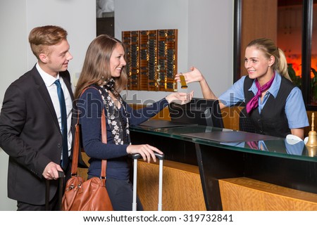 receptionist at hotel reception handing over a key to guest or customer