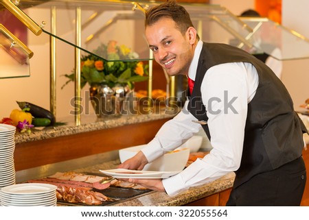 Catering service employees filling buffet at a restaurant or hotel