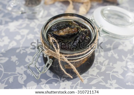 Dried plums with herbs  in a transparent jar. Selective focus