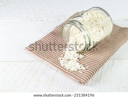 Rice grain in glass bottles on brown cloth on wooden background