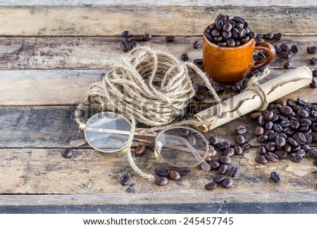 Old paper roll, glasses, rope reel and coffee beans on wooden background