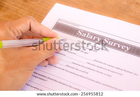 Hand with pen choosing salary survey from on the table