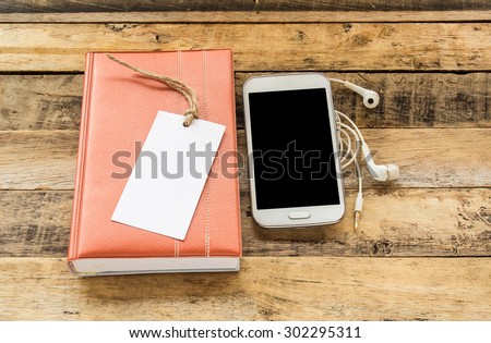 Notebook,smart phone and earphone on wooden table background