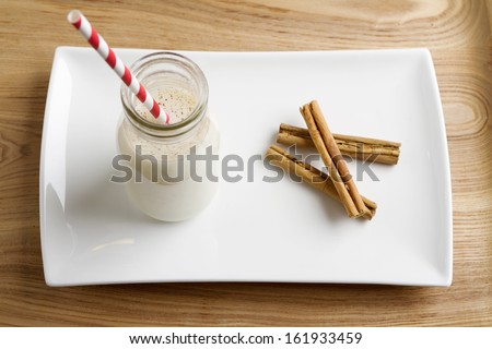 Christmas Egg Nog in a mini milk pot with cinnamon on a white plate
