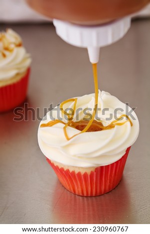Salted caramel topping applied to vanilla cupcake