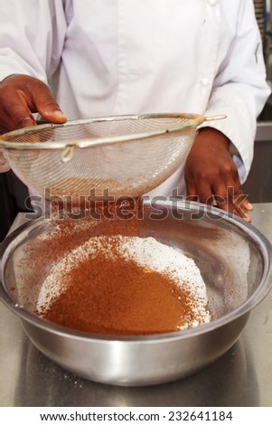 Close up of a pastry chef sifting cocoa into flour mix