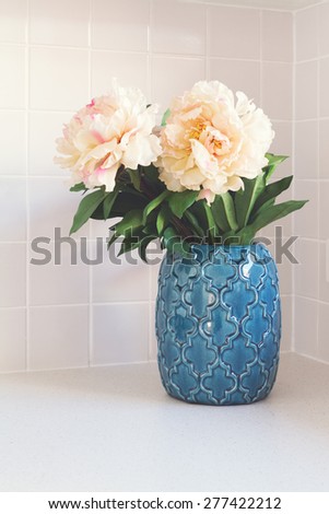 Blue moroccan vase with large white flowers on kitchen bench
