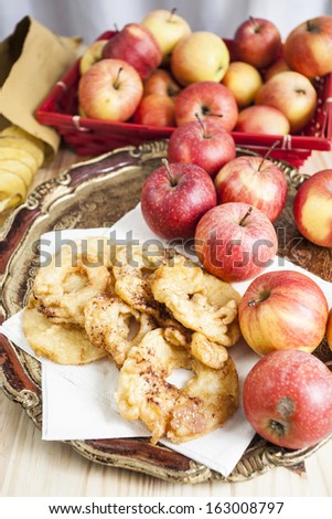 Apple fritters on an elegant wooden tray with many fresh apples near