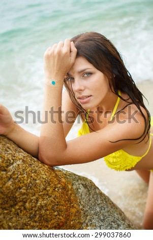 Relaxing beach woman enjoying the sea in swimsuit. Glamorous girl with gold tattoo on the hand.