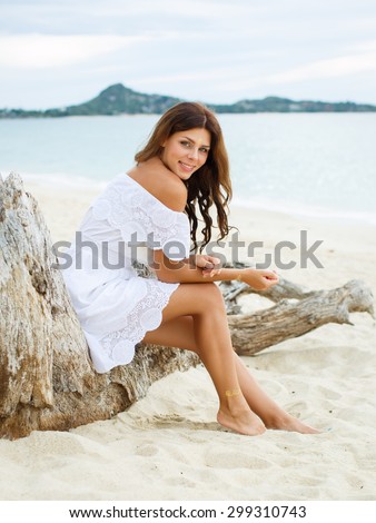 Beautiful woman enjoying the summer sun in white dress. Glamorous girl with gold tattoo on the hand.
