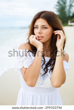 Beautiful woman enjoying the summer sun in white dress. Glamorous girl with gold tattoo on the hand.