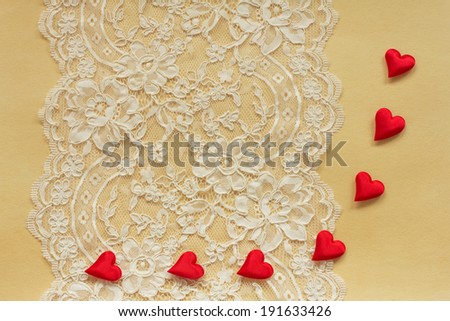 Beautiful lace on old paper with red satin hearts