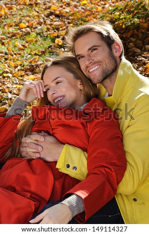 Young beautiful smiling couple in the park at fall - autumn, leaves, sunny day, fall