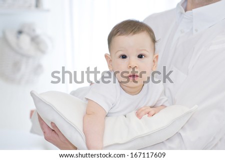 Portrait of a father with his lovely baby boy on white pillow