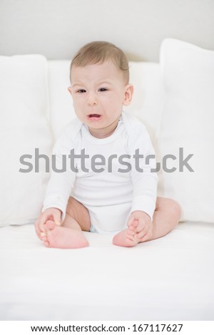 Portrait of crying baby boy in white. Little Angel