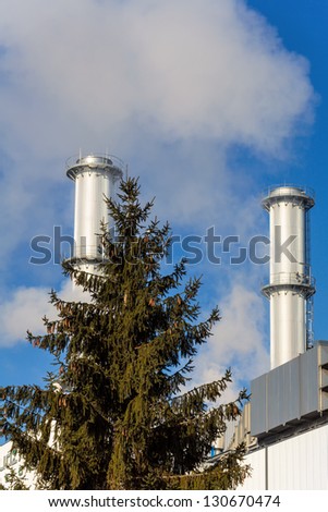 chimney of an industrial company with tree. symbolic photo for environmental protection and ozone.