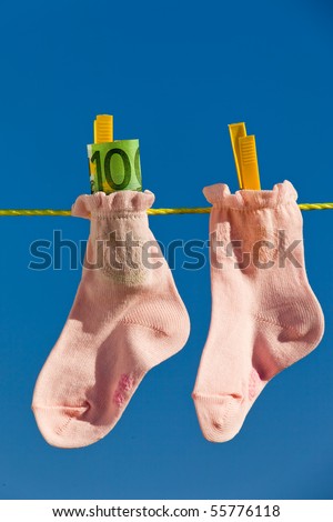 baby socks on laundry line with Euro bank notes. Blue sky.