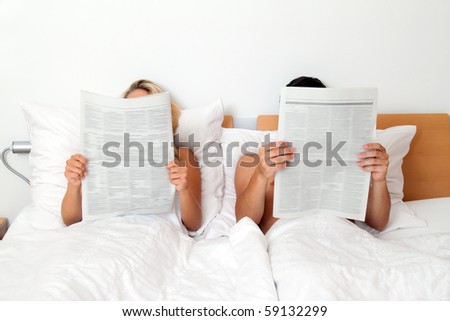A young couple in bed reading a newspaper. Information and news