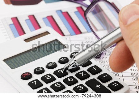 A calculator with graphics of a balance sheet. Sales, profit and operational costs.