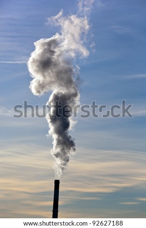 the smoking chimneys of a factory against a blue sky. white smoke rises from chimneys on