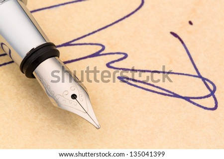 a fountain pen and a signature on yellow paper. symbolic photo for contract testament and graphology