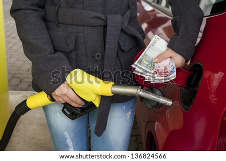 a young woman at a gas station gasoline tank. the cost of the car because of the gas prices are getting more expensive