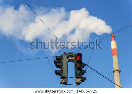 chimney of an industrial company and a red traffic light. symbolic photo for environmental protection and ozone.