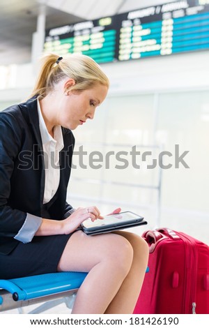 a business woman using her tablet computer at an airport. mobility and communication in business. roaming charges when abroad.