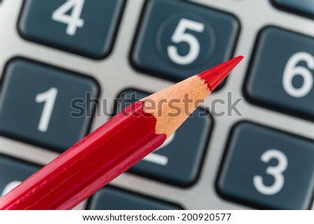 a red pen is on a calculator. save on costs, expenses and budget for bad economy