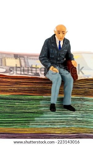 symbol photo for retirement and old age, figure of an old man sitting on a stack of bills