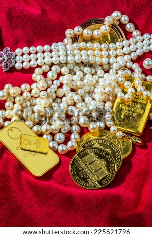 gold coins and bars with decorations on red velvet. symbol photo of wealth, luxury, wealth tax.