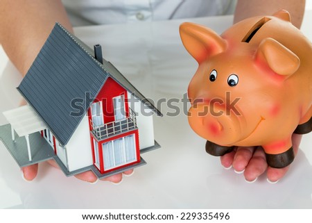 a woman with a house and a piggy bank. the right financing for the home purchase.