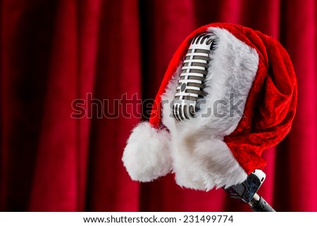 an old retro microphone with santa hat against a red velvet background.