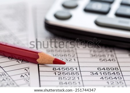 a calculator is on a balance sheet numbers are statistics. photo icon for sales, profits and costs.