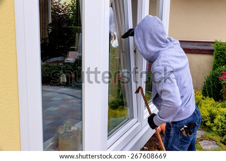 a burglar trying to break in an open window with a crowbar