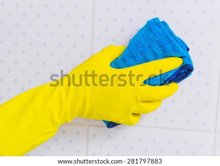 the tiles of a bathroom is cleaned with latex gloves.
