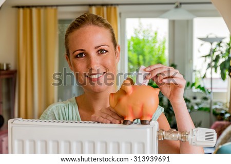 a young woman with a radiator and a piggy bank. symbolic photo for saving energy and heating