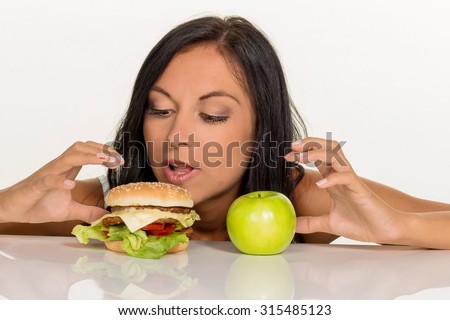 a young woman can not decide between a hamburger and an apple itself. healthy or unhealthy diet.