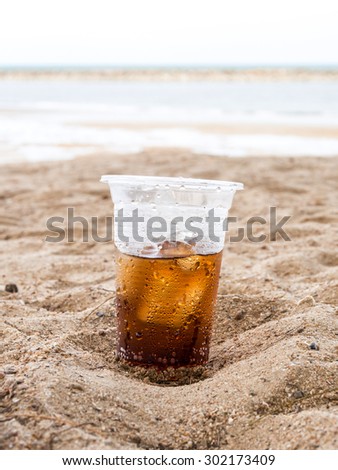 Hot summer glass plastic sparkling water in sand
