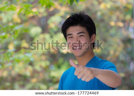 smiling asian cool young man thump up  with green background