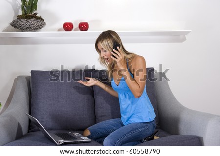 surprised woman on her couch with her cellphone and laptop