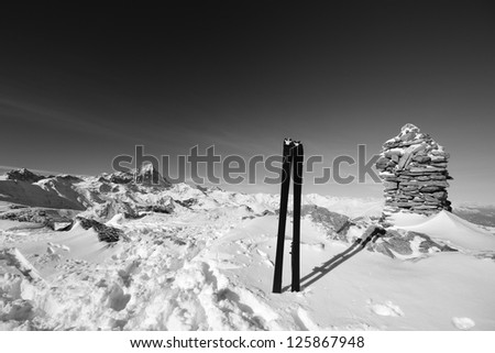 Black and white view of a pair of back country ski on the top of the mountain in a clear bright day and scenic winter background