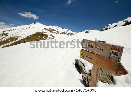 Footpath\'s wooden signposts in scenic snowy mountain landscape. Location: western Alps, Piedmont, Italy.