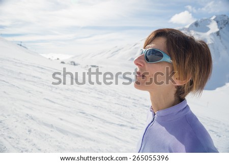 Adult female skier with backpack and sunglasses watching the sun in the ski resort of La Thuile, Aosta Valley. Italian french Alps. Concepts of spending free time on famous mountain areas.